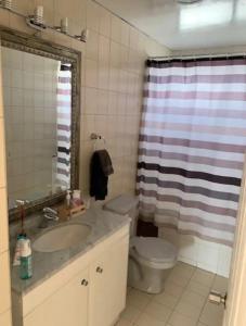 ein Badezimmer mit einem Waschbecken, einem WC und einem Duschvorhang in der Unterkunft DEPARTAMENTO PISO 5 FRENTE AL MAR in Antofagasta