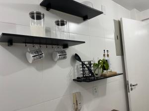 a kitchen with black shelves and cups on the wall at Village blue AC Wi-Fi piscina in Cabo Frio