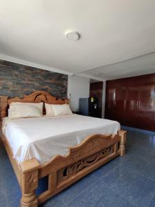 um quarto com uma grande cama de madeira com lençóis brancos em Hotel - La Perla Del Caribe em Ríohacha