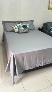 uma cama grande com um cobertor cinzento e almofadas em Maresia 7B em Salvador
