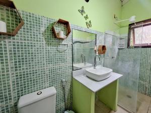 Baño de azulejos verdes con lavabo y aseo en Hostel Alto Astral - Lagoa, en Morro de São Paulo