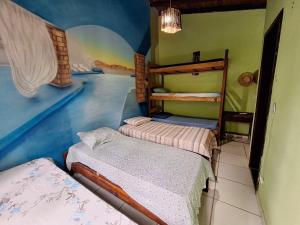 1 dormitorio con 2 camas en una habitación con un mural en Hostel Alto Astral - Lagoa en Morro de São Paulo