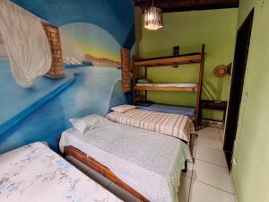 1 Schlafzimmer mit 2 Betten in einem Zimmer mit Wandbild in der Unterkunft Hostel Alto Astral - Lagoa in Morro de São Paulo