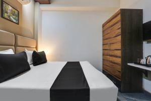a bedroom with a black and white bed and a wooden cabinet at OYO Flagship Hotel V Town in New Delhi