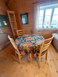 a dining room table with a flowered table and chairs at Valen Cabins in Reine in Reine