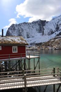 a red house on a dock next to a mountain at Valen Cabins in Reine in Reine