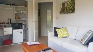Mangawhai Heads apartment في مانجاواي: غرفة معيشة مع أريكة بيضاء وطاولة