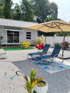 a pair of chairs and an umbrella in front of a house at Casa LiLa Tiny Stay & Pool Kota Bharu,free wifi,free parking 
