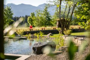 a pond in a garden with a person in the background at Das Talgut in Ofterschwang