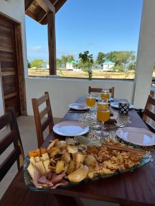 a table with a plate of food and glasses of orange juice at Belizima Eco Resort in Sarteneja