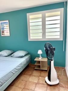 - une chambre bleue avec un lit et un ventilateur dans l'établissement La Yole - appartement, à Bois-Neuf