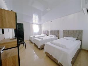 um quarto com 3 camas e uma secretária. em Casa Los Almendros, Valledupar casa completa em Valledupar