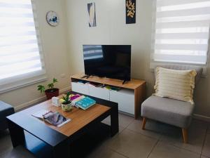 a living room with a table and a tv and a chair at Casa Aloe Villarrica con Aire Acondicionado in Villarrica