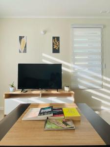 sala de estar con TV y mesa de centro en Casa Aloe Villarrica con Aire Acondicionado, en Villarrica