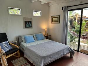 a bedroom with a bed and a chair and a window at Lunas del Bosque Cabaña y apartamento en suite in La Paloma