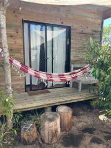 a hammock in front of a wooden cabin at Lunas del Bosque Cabaña y apartamento en suite in La Paloma