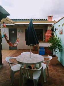 einen Tisch mit einem Sonnenschirm auf einer Terrasse in der Unterkunft Kitnet da Elô in Tramandaí