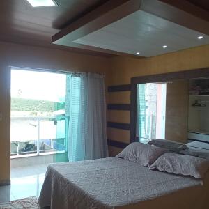 a bedroom with a bed and a large window at Centro da cidade, ótimo lugar in Caparaó Velho