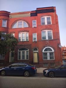 two cars parked in front of a red brick building at HUGE 2 bedroom Apt FREE street parking (king bed) in Baltimore