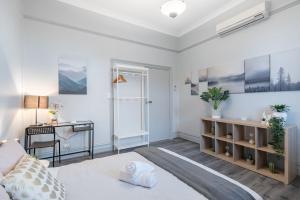 Habitación blanca con cama y escritorio. en Boutique Private Room Situated in the Heart of Burwood - SHAREHOUSE en Sídney