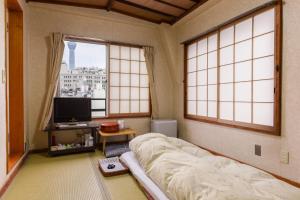 a bedroom with a bed and a tv and windows at Ryokan Mikawaya in Tokyo