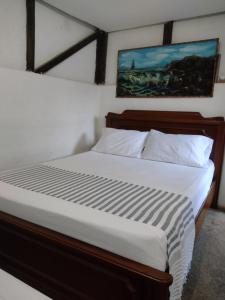 a bedroom with a large bed with white sheets at Sapiens house "cabaña del Río" in Cali