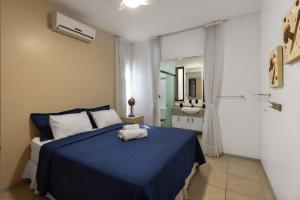 Un dormitorio con una cama azul con una toalla. en Oceanview A102 - PÉ NA ÁREA - perto do centro, 2 dormitórios, piscina, cozinha, 116m2, en Cumbuco