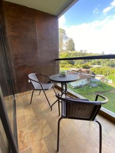 un patio con mesa, sillas y una ventana grande en Suite Llanogrande, en Rionegro
