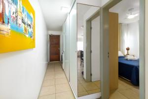 um corredor com um espelho e uma cama num quarto em Oceanview A102 - PÉ NA ÁREA - perto do centro, 2 dormitórios, piscina, cozinha, 116m2 em Cumbuco