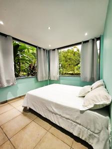 sypialnia z dużym łóżkiem i 2 oknami w obiekcie Sítio do Sossego w mieście Cachoeiras de Macacu