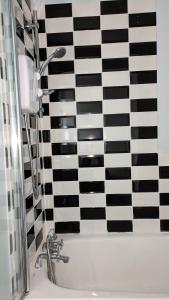 a bathroom with a black and white checkered wall at Southsea in Coedpoeth +10 photos