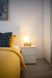 Just4u Apartment في ألمادا: غرفة نوم بسرير اصفر مع مصباح على الموقف الليلي