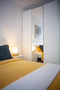 1 dormitorio con cama amarilla y espejo en Just4u Apartment, en Almada