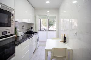 a white kitchen with a table with a bottle of wine at Just4uApartment - Near Lisbon & Beach - With AC in Almada