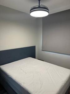 1 dormitorio con cama blanca y luz en Belo Studio com suíte e varanda en São Paulo