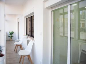 una stanza con una porta a vetri e due sedie bianche di Just4u Apartment ad Almada