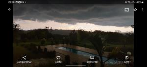 a view of a pool in a yard with a cloudy sky at Sítio Santa Cecília in Itapetininga +3 photos