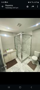 a bathroom with a shower and a toilet and a sink at Serenity Condo in Piarco