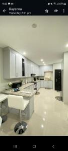 a large kitchen with white cabinets and a white floor at Serenity Condo in Piarco