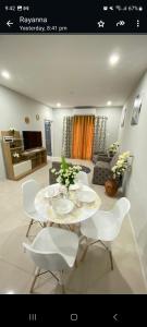 uma sala de estar com uma mesa e cadeiras brancas em Serenity Condo em Piarco