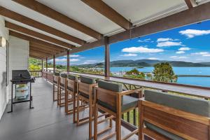 a balcony with chairs and a grill and a view of the water at Sailor's Lookout in Airlie Beach