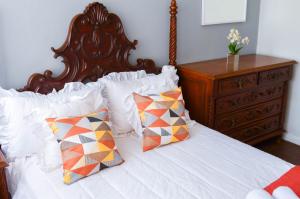 a bedroom with a bed with white sheets and pillows at Refúgio pra sua família in Guarapari