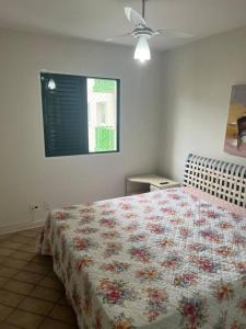 una camera da letto con un letto con copriletto floreale di Cond. Clube Riviera S. Lourenço a Bertioga