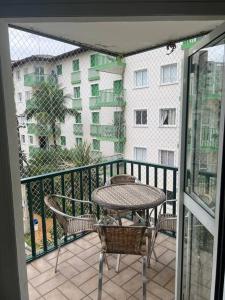 un balcone con tavolo e sedie e un edificio di Cond. Clube Riviera S. Lourenço a Bertioga