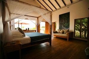 C Beyond Nilaveli في نيلافيلي: غرفة نوم مع سرير مظلة وأريكة