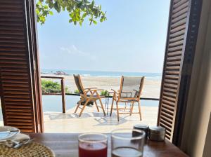 a table and chairs on a balcony with a view of the beach at C Beyond Nilaveli in Nilaveli