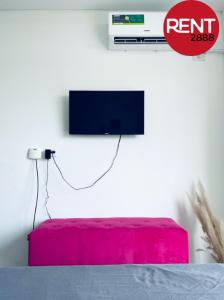 Habitación con TV en la pared y taburete rojo. en Rent Balbin en Buenos Aires