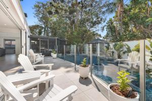 un patio con sillas blancas y una piscina en 5BR Mermaid Waters Luxury Home, en Gold Coast