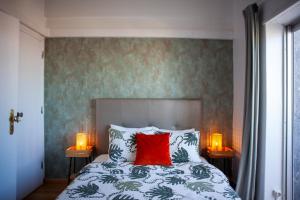ein Schlafzimmer mit einem Bett mit rotem Kissen und zwei Lampen in der Unterkunft Just4uApartment 2 - Near Lisbon & Beach - With AC in Almada