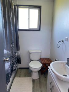 ein Bad mit einem WC, einem Waschbecken und einem Fenster in der Unterkunft Cabaña Raihuè Austral in Puerto Montt